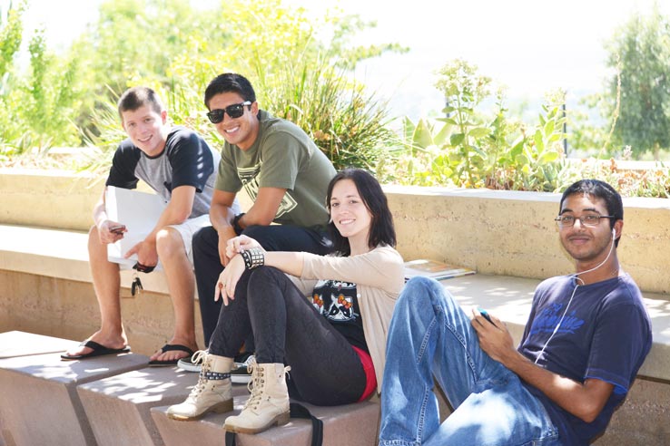 Four students sitting down together outside.